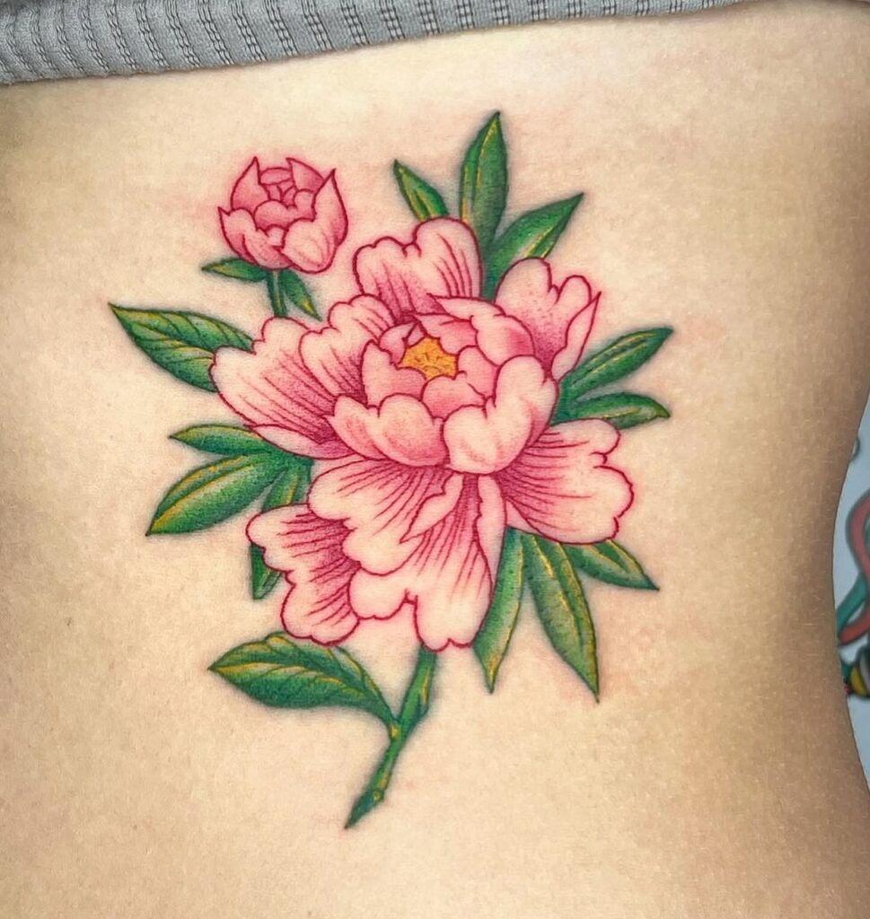 Tatuaje hecho en Barcelona de una flor rosa estilo realista con hojas verdes, en la zona lateral del abdomen. Los pétalos tienen un sombreado en tonos rosados con detalles delicados, y las hojas muestran un degradado verde con toques amarillos.
