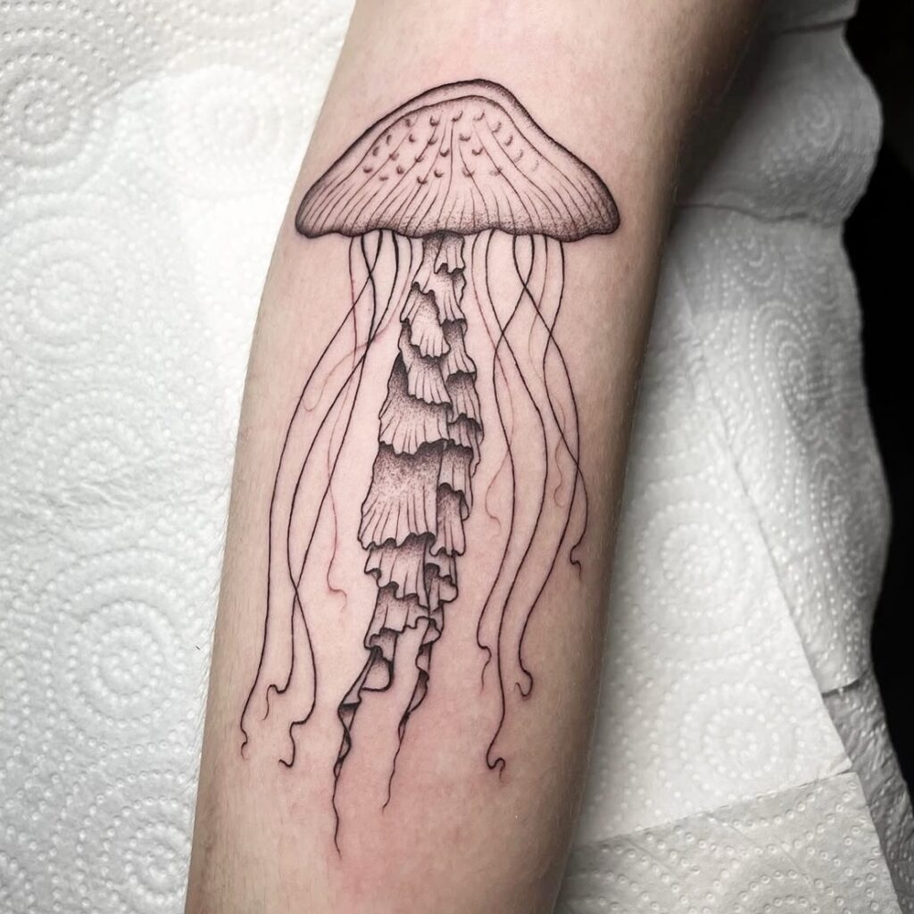 Tatuaje lineal de una medusa con detalles en puntillismo y tentáculos finos, hecho en Barcelona.