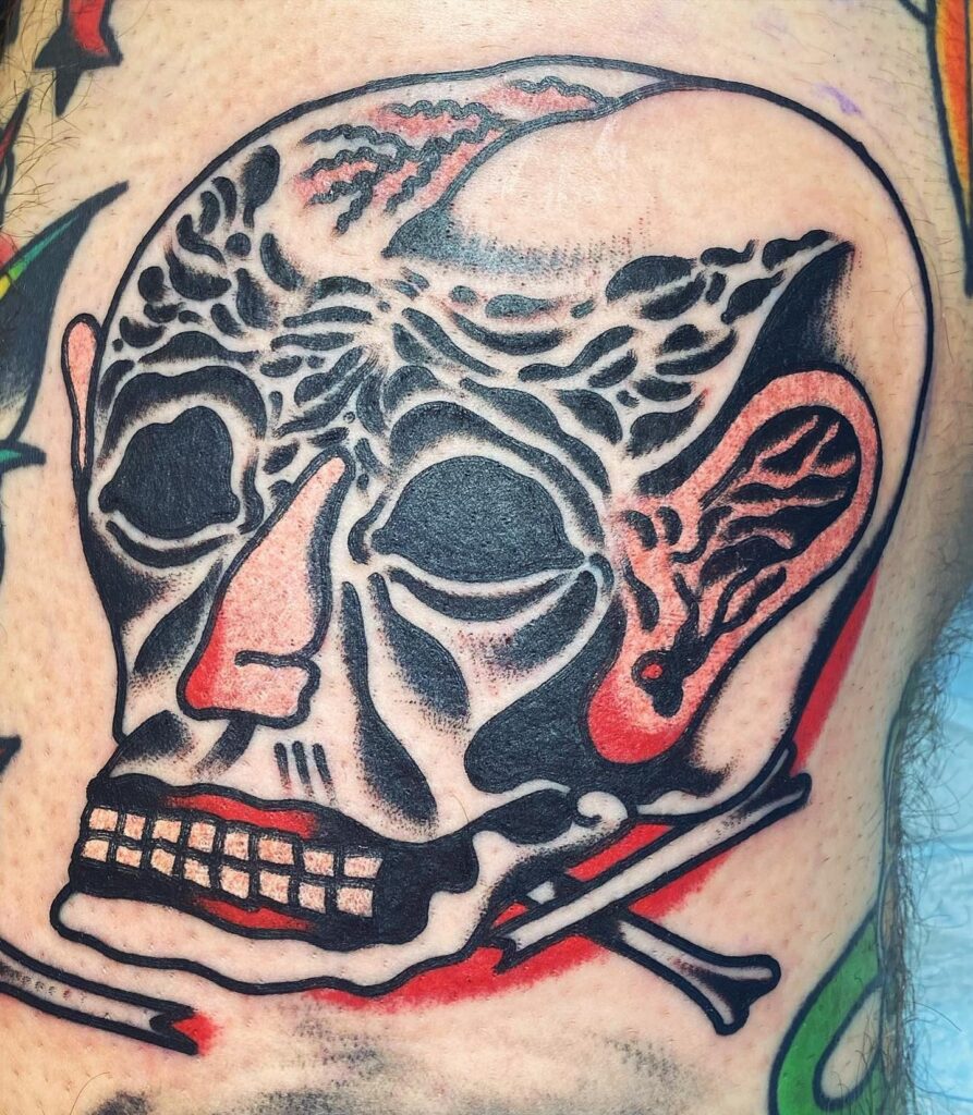 Tatuaje de una calavera con detalles negros y rojos en estilo tradicional, hecho en Barcelona.