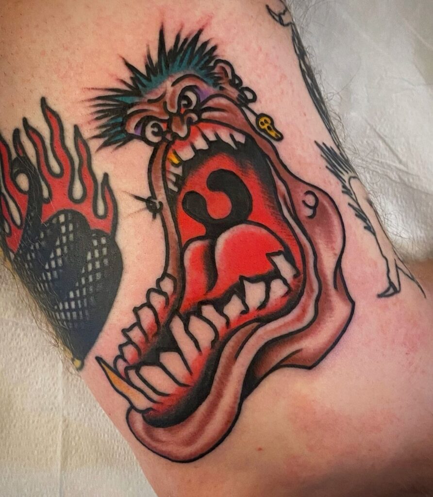 Tatuaje a color de una cara estilo punk con gran boca abierta, realizado en Barcelona.
