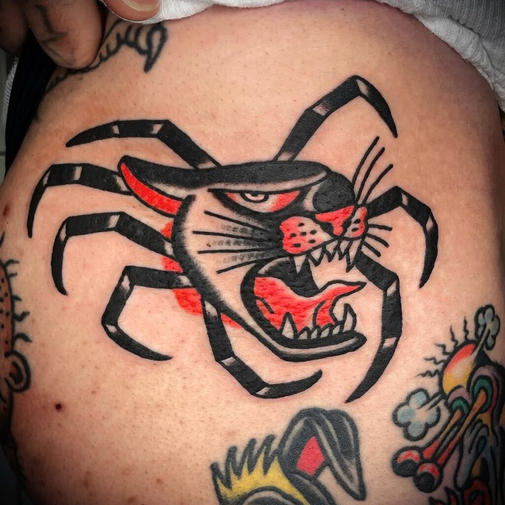 Tatuaje estilo old school realizado en Barcelona, representando una pantera con cuerpo de araña, en tinta negra y roja, con líneas gruesas y sombreado simple.