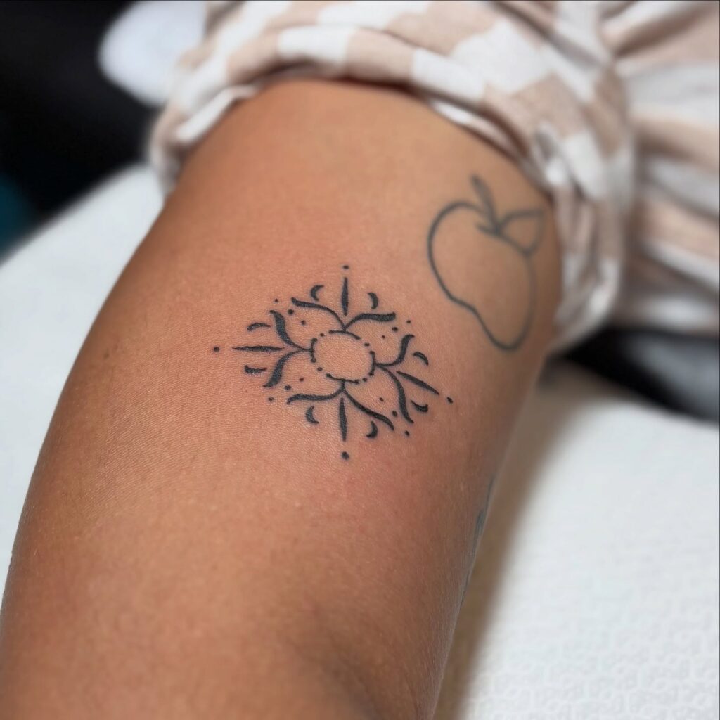 Tatuaje ornamental pequeño con diseño floral minimalista, realizado en Barcelona