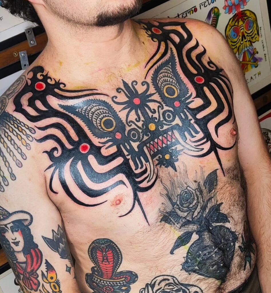 Tatuaje grande en el pecho de una serpiente enrollada alrededor de una mano con varias aves, hecho en Barcelona.